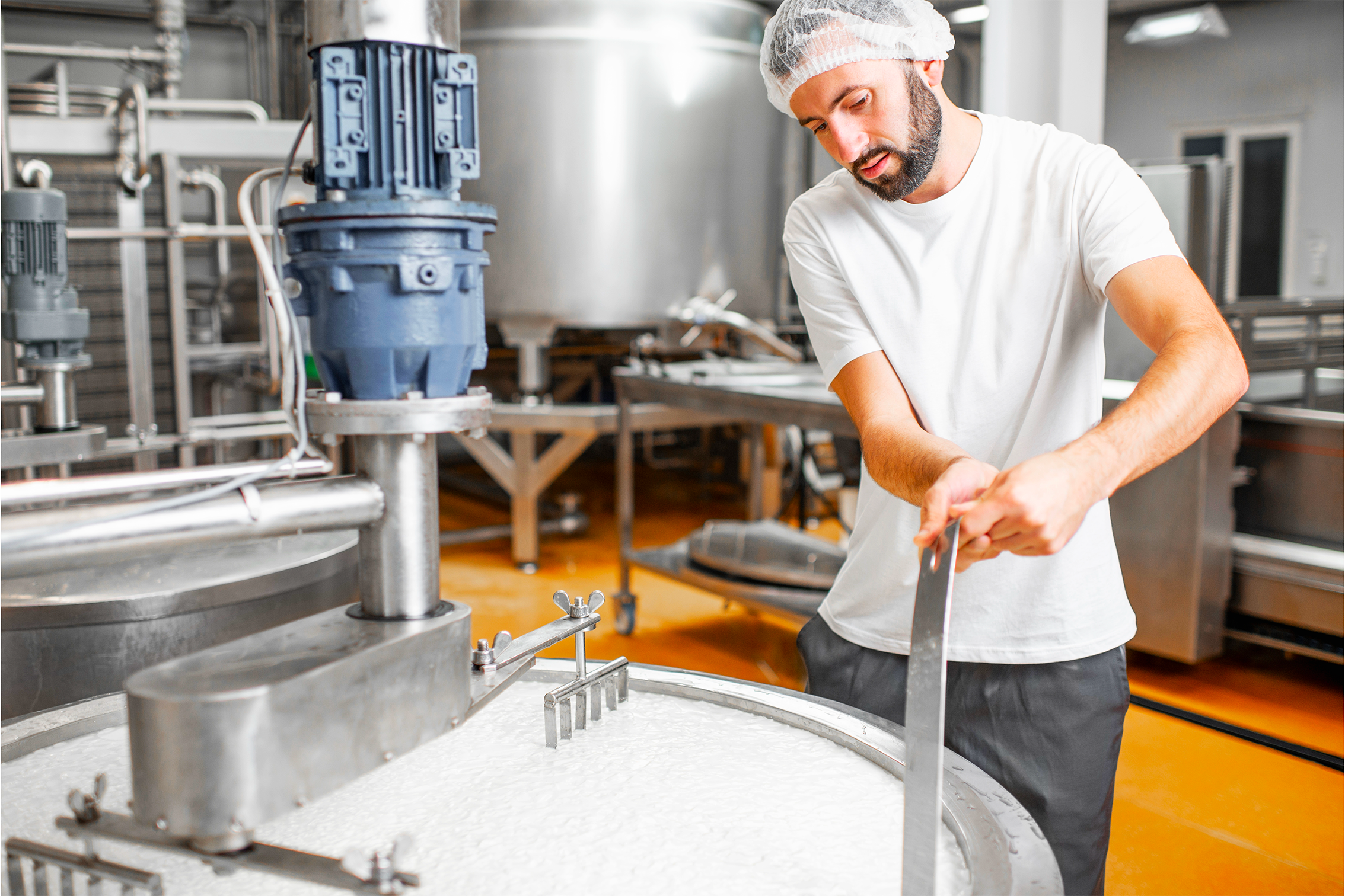 Casaro all'interno del laboratorio sta girando il mestolo nel calderone contenente caglio e latte