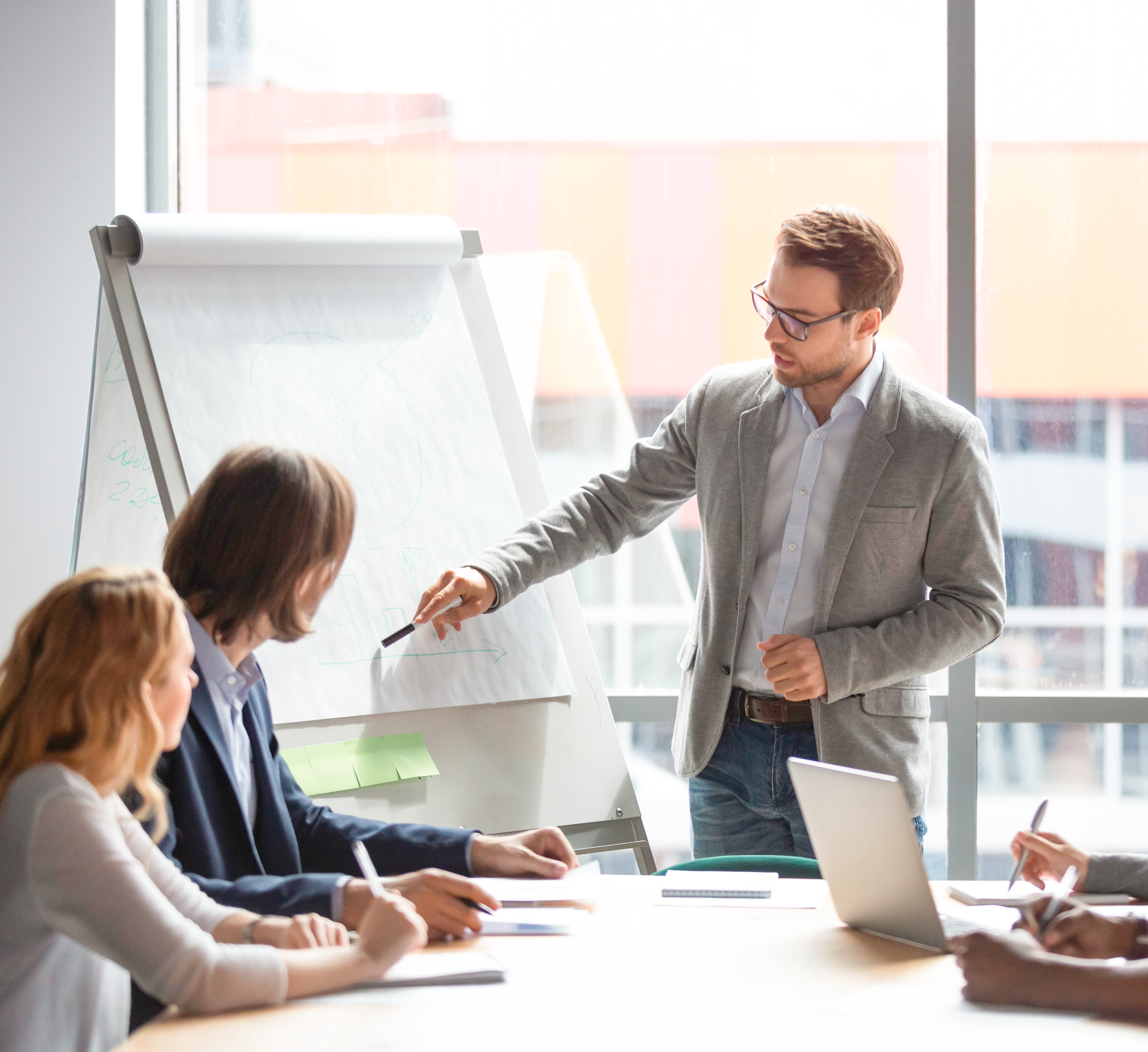 Un Consulente sta facendo formazione al personale, formato da quattro persone, all'interno di una sala riunioni di un'azienda .