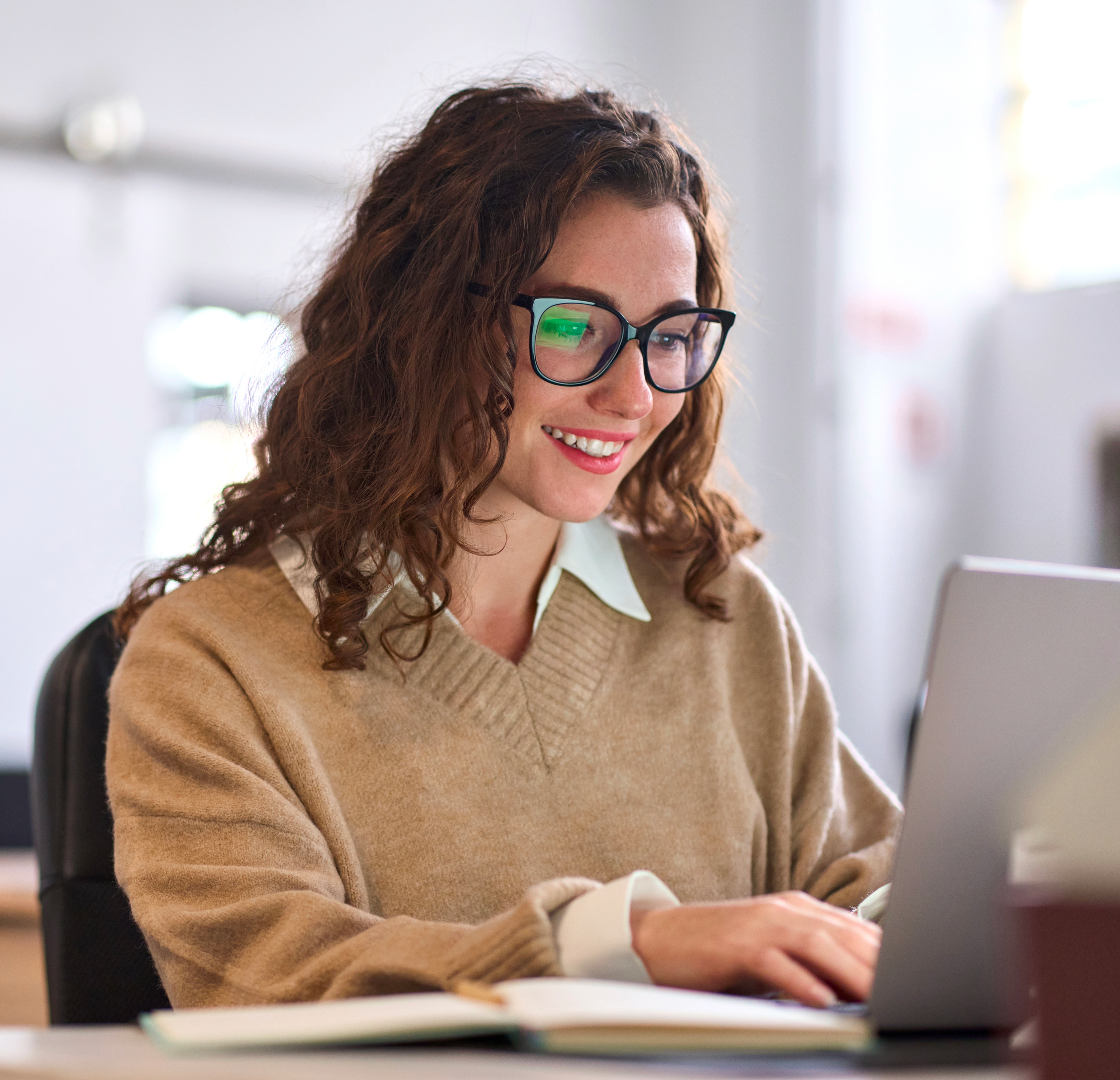 Una giovane professionista sta sorridendo mentre lavora sul computer portatile, sta guardando lo schermo.