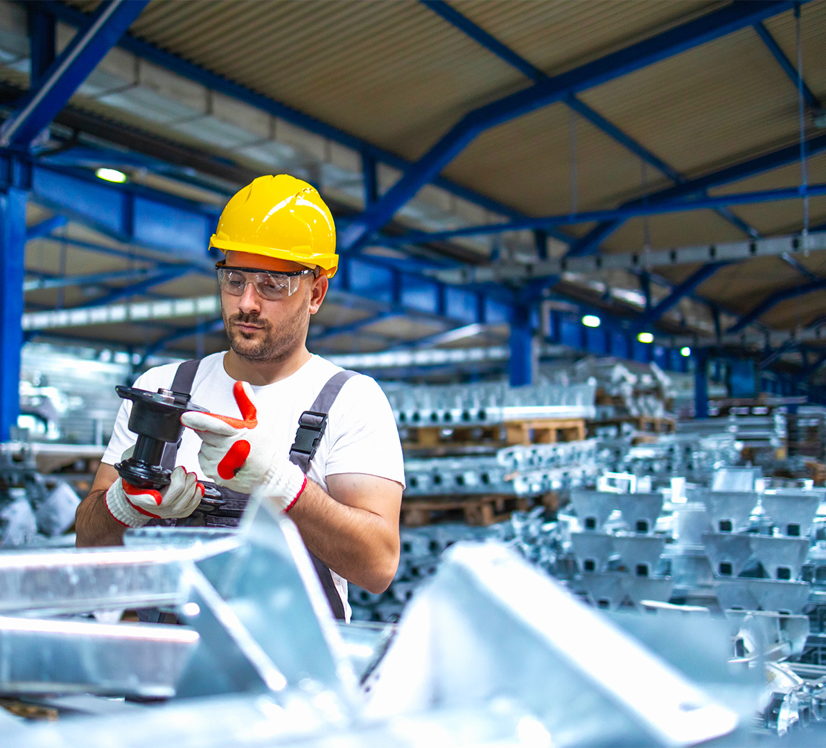 Operaio lavora in un magazzino in mezzo ad una catasta di materiali metallici