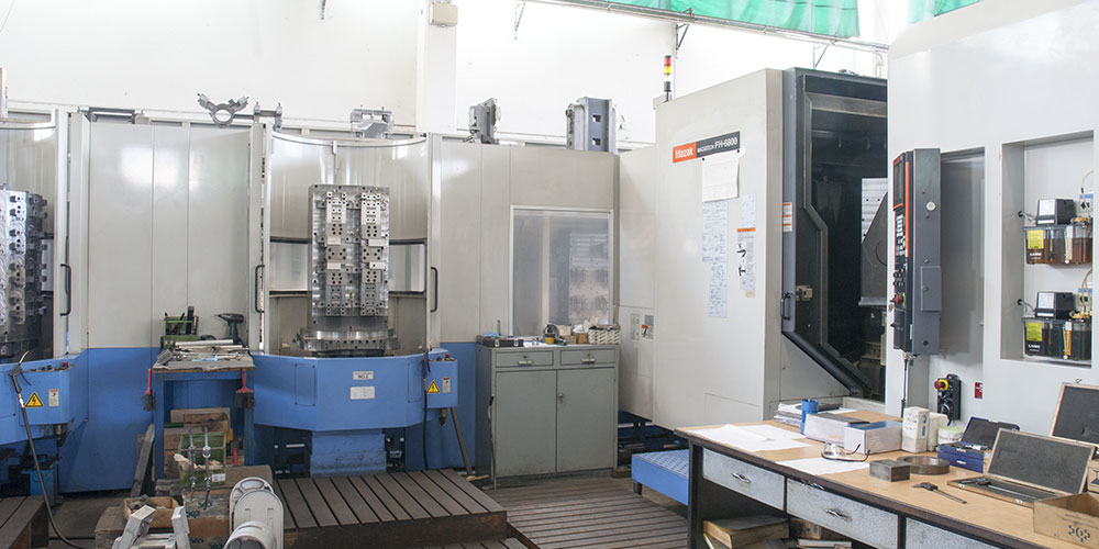 Interno di un'officina meccanica di precisione con centri di lavoro CNC Mazak e banchi di lavoro attrezzati.